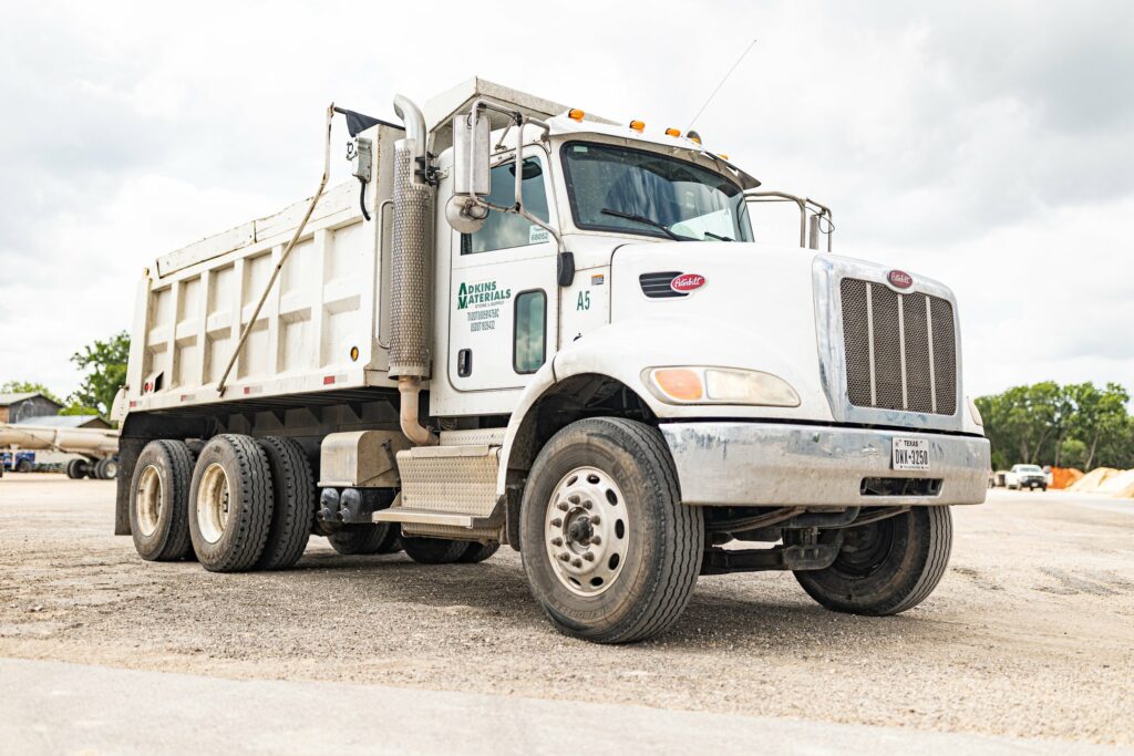 White dump truck with Adkins Materials logo.